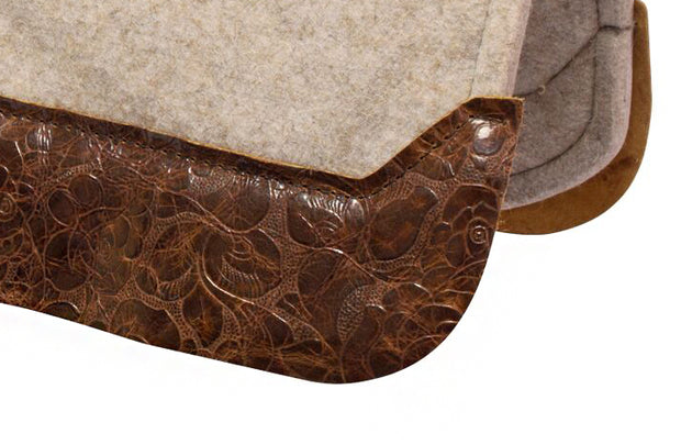 Close up of brown floral wear leather on a tan felt saddle pad