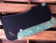 Black saddle pad with teal floral leather laying on pallet